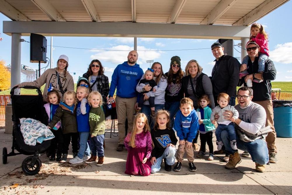 A group of family, friends and kids smile for a photo during Homecoming 2023