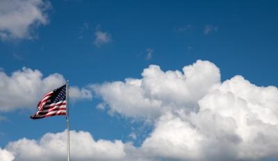 American flag flies over blue, cloudy sky